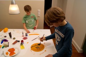 Zwei Jungs malen an einem Tisch mit viel Bastelzeug.