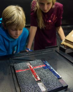Ein Mädchen und ein Junge betrachten eine Seite aus Buchstabenformen.
