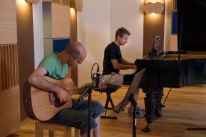 Zwei Männer, Moritz und Andreas, spielen Gitarre und Klavier.