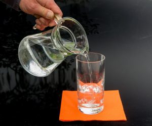 Ein Karaffe gießt Wasser in ein Glas.