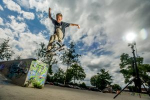 Der Junge Bennet springt in einem Park von einem Vorsprung mit einem Skateboard.