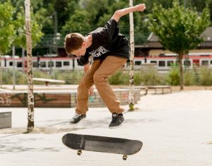 Der Junge Bennet macht mit seinem Skateboard einen Kickflip.