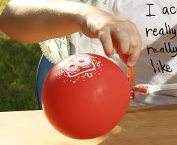 Ein Mädchen entfernt die Klammer von einem Luftballon.