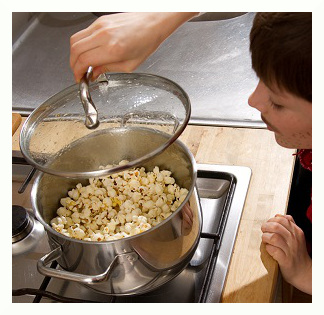 Ein Junge schaut auf einen großen Topf voller Popcorn.
