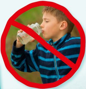 Ein Junge trinkt gefiltertes Wasser. Um ihn herum ist ein rotes Verbotszeichen aufgemalt.