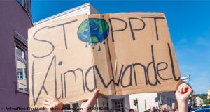 Ein großes Schild aus Pappe hat die Aufschrift: Stoppt den Klimawandel.