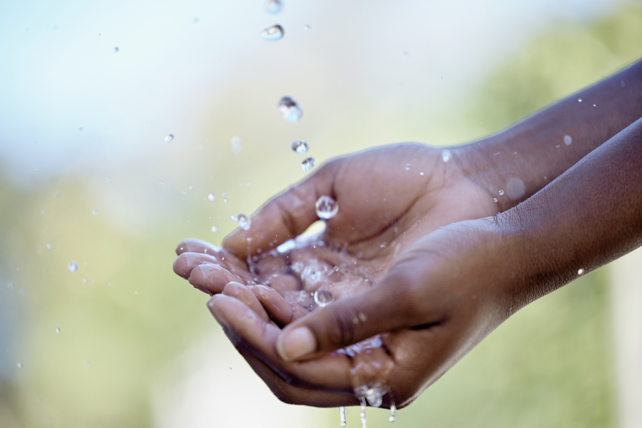 Wasser sparen: Hände fangen die Tropfen eines Wasserstrahls auf.